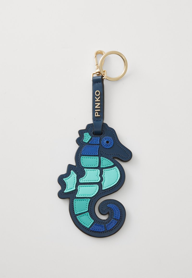 Chaveiro de couro azul-marinho em forma de cavalo-marinho, com detalhes em azul e verde-água e um anel dourado. Superfície texturizada com elementos de design em camadas.
