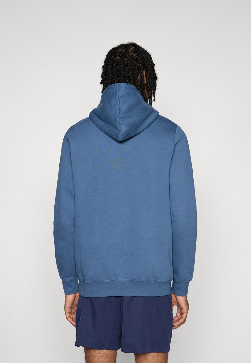 Blauwe hoodie van zachte stof; voorzien van een kangoeroezak, geribbelde boorden en zoom. De achterkant toont de capuchon en de gladde textuur.