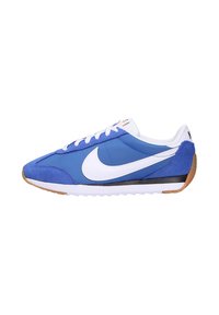 Chaussures de sport bleues avec un logo swoosh blanc, présentant un mélange de matériaux en daim et en textile, des lacets plats et une semelle extérieure en caoutchouc gomme.