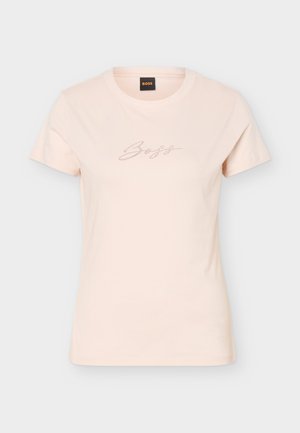 Világos bézs rövid ujjú női póló kerek nyakkivágással és kis pöttyözött "Boss" felirattal a mellkasán.