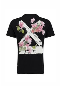 Camiseta negra con un gran diseño de X en trazo de pincel blanco en la parte de atrás, decorada con racimos de flores rosas y hojas verdes.