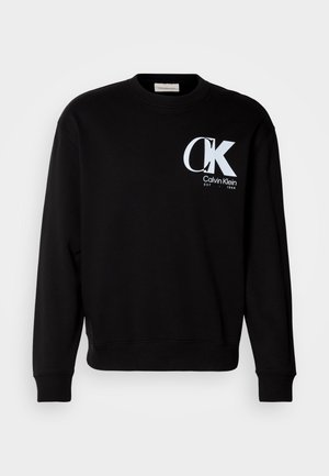 Černá mikina vyrobená z bavlny s žebrovaným výstřihem a manžetami. Na přední straně je bílý logo "CK" a text "Calvin Klein EST 1968".