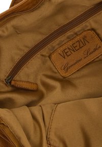 Brown genuine leather interior with a zippered pocket. A tag displays "VENEZIA Genuine Leather" embossed on a textured leather patch.