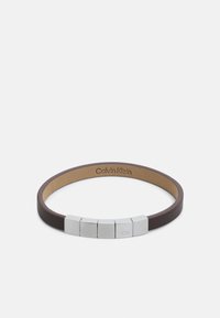 Brown leather bracelet with five silver metal accents featuring a CK logo, smooth texture, minimalist design, and adjustable fit.