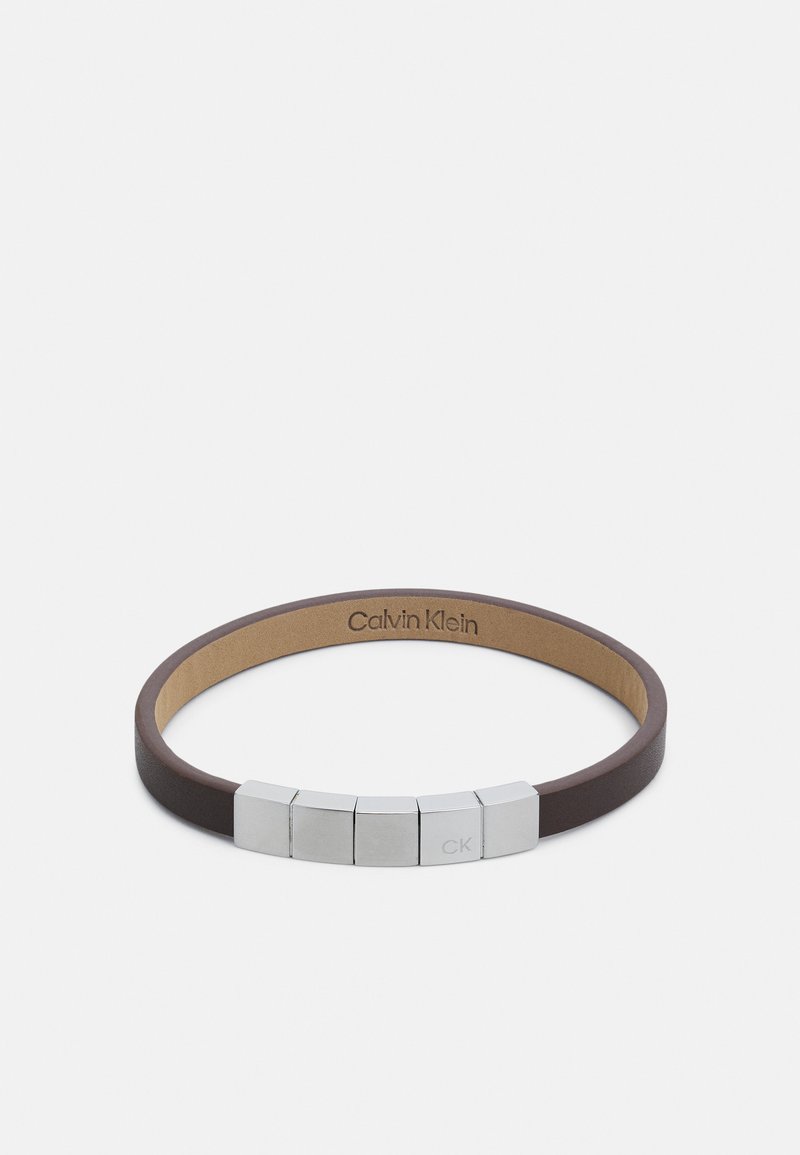 Brown leather bracelet with five silver metal accents featuring a CK logo, smooth texture, minimalist design, and adjustable fit.