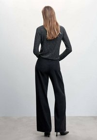 Pantaloni neri a gamba larga in denim, abbinati a un top fitted a maniche lunghe di un grigio scuro. Il tessuto ha una leggera lucentezza e una texture morbida.