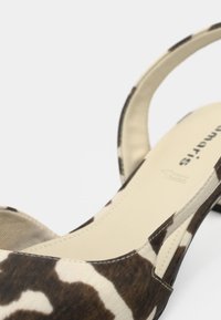 Sandale à talons hauts imprimé animal marron et crème avec un bout arrondi et un dos ouvert, présentant une surface texturée et un design minimaliste.