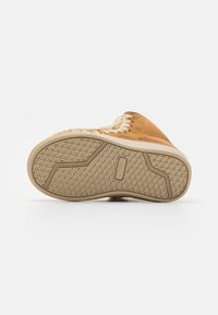 Chaussure slip-on en daim avec une semelle texturée beige ; présente un détail en tresse sur le dessus. Le design de la semelle comprend des rainures en motif de diamant.
