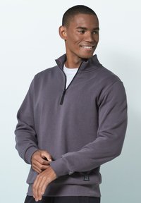 Gray zip-up sweatshirt made of soft fabric, featuring a high collar, ribbed cuffs, and a side tag for added detail.