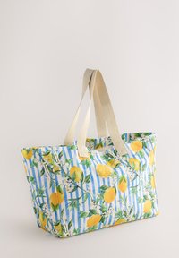 Large tote bag with a blue and white striped pattern, adorned with lemon and floral prints; features beige fabric handles.