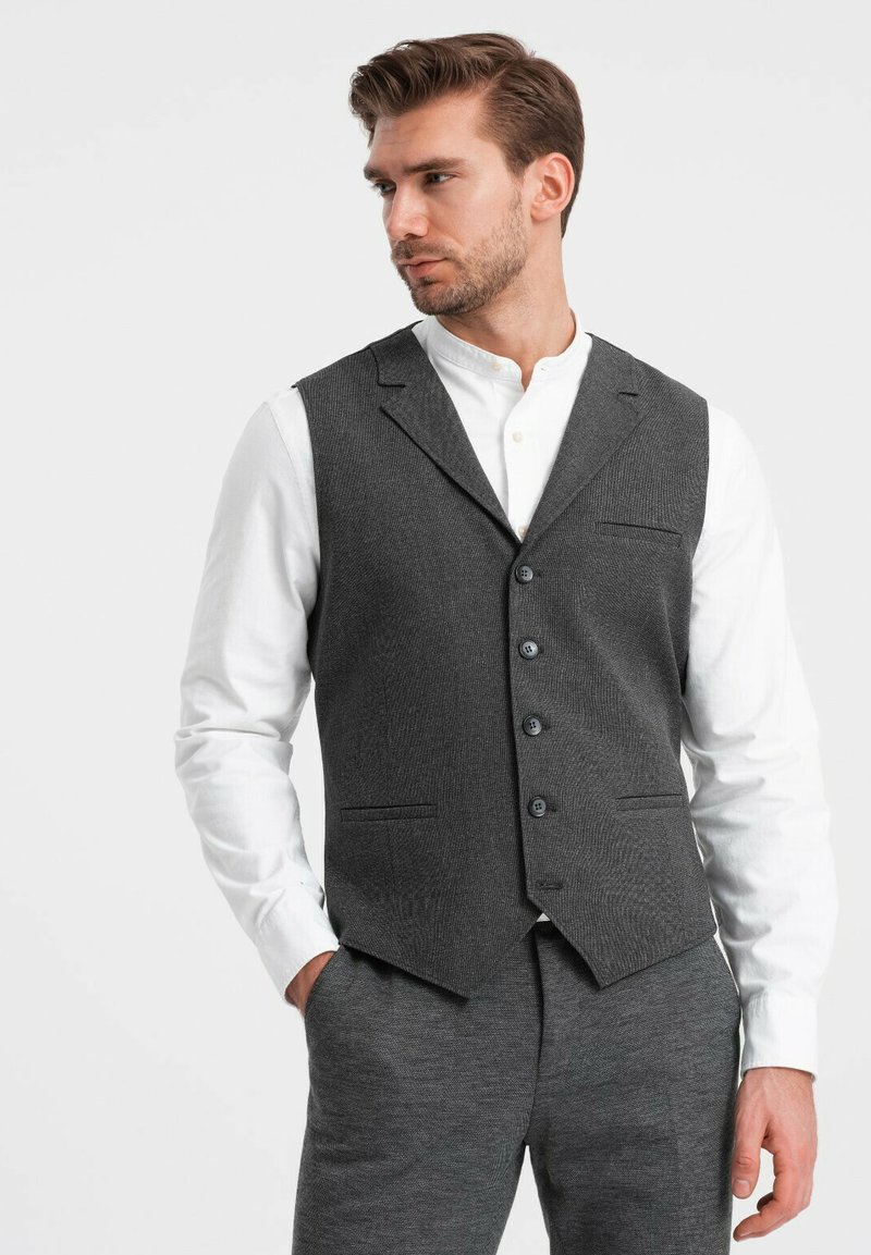 Grijs vest met een visgraatpatroon, voorzien van vijf knopen, notch revers en twee zakken, gecombineerd met een witte overhemd met kraag en grijze broek.