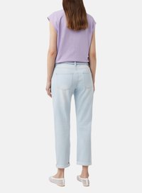 Jasnoniebieskie dżinsy o prostym kroju z podwiniętymi mankietami, zestawione z różową bluzką z krótkim rękawem. Casualowy, miękki materiał i luźny krój.