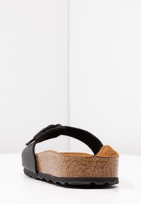 Sort sandal med en cork-fodbed, tekstureret gummisål og et enkelt justerbart rem. Enkel, åben tå design.
