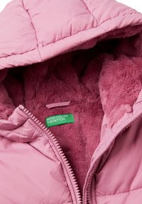 Różowa kurtka puchowa z pikowaną zewnętrzną warstwą, miękką ociepliną z sztucznego futra oraz zieloną metką z nazwą marki. Zapięcie na zamek błyskawiczny z przodu.