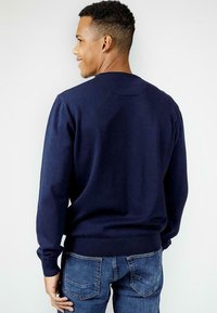 Granatowy sweter dziane z okrągłym dekoltem, ściągaczami przy mankietach i u dołu, pokazany z tyłu na osobie noszącej dżinsy.