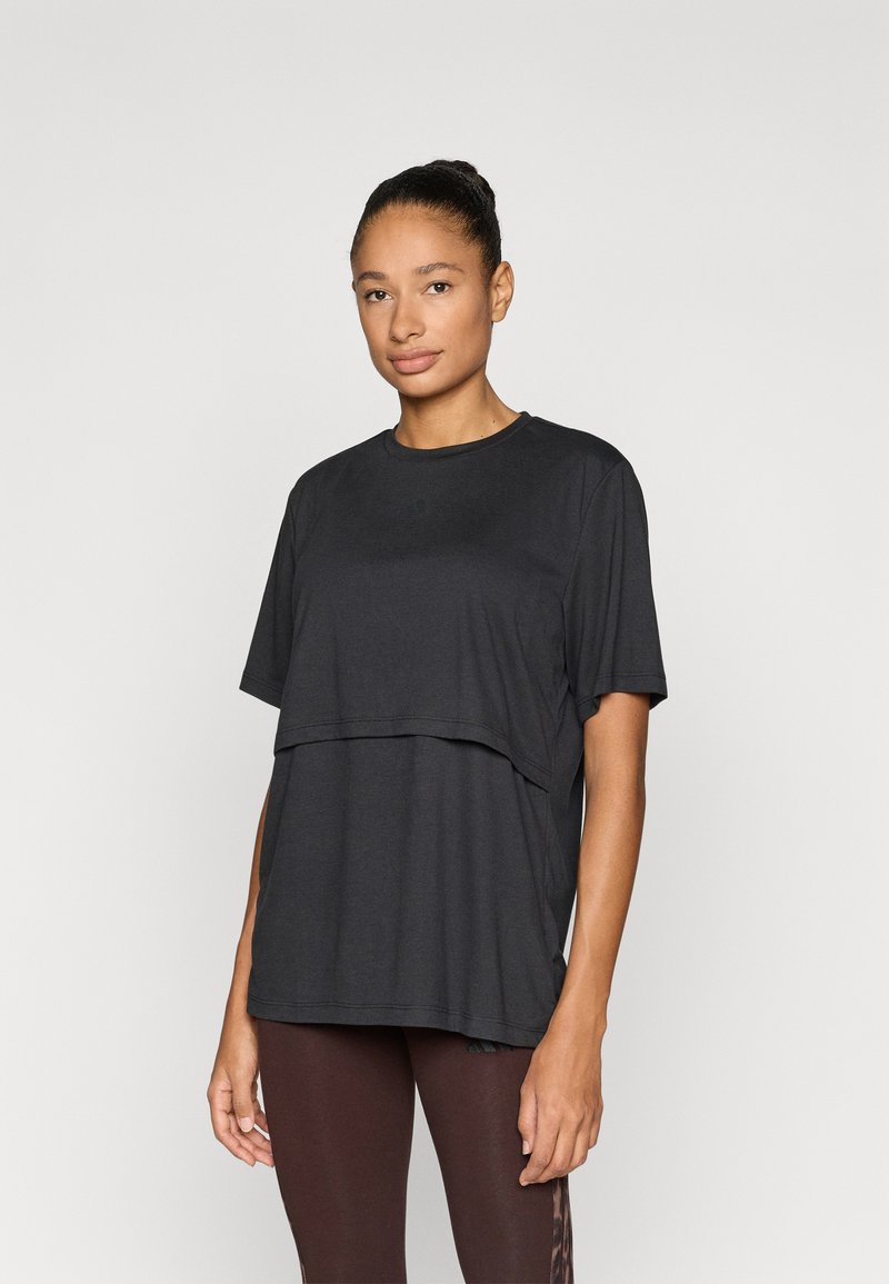 Μαύρο τοπ με κοντά μανίκια και στρωματοποιημένο σχέδιο, κατασκευασμένο από απαλό υλικό. Διαθέτει στρογγυλή λαιμόκοψη και χαλαρή γραμμή, συνδυασμένο με καφέ κολάν.