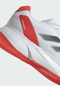 Zapatilla deportiva blanca con parte superior de malla, acentos rojos, suela texturizada y detalles reflectantes. Presenta la marca "DURAMOSL" y "LIGHT-MOTION".