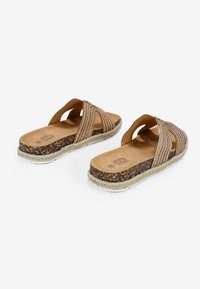 Brown slide sandals with cork footbed, textured fabric straps in a diagonal pattern, and a braided jute sole detail.