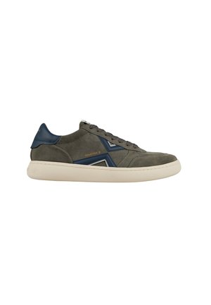 Low-top sneaker in olijfgroen suède met donkerblauwe accenten, beige zool, veterluiting aan de voorkant en "SMITH X" branding op de zijkant.