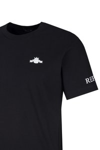Schwarzes T-Shirt mit kurzen Ärmeln, mit kleinem weißen Wappen-Logo auf der linken Brust und teilweise weißem "REPLAY"-Text auf dem rechten Ärmel.