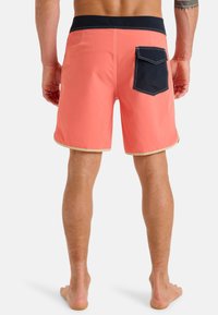 Pánské korálové plavky s námořnickým páskem; mají zadní kapsu s modrým prošíváním a béžovým lemem podél otvorů na nohy.