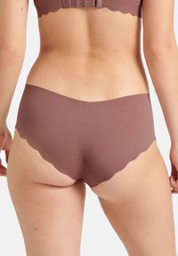 Bruine naadloze onderbroeken met een scalloped randontwerp, gemaakt van soepel materiaal. Het achteraanzicht toont een slipvorm met minimale bedekking.