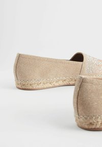 Beige espadrilles yang dibuat dari kain tekstur dengan sol jute anyaman dan dihias dengan payet halus di sepanjang tepi atas.