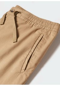 Pantalon en coton beige avec ceinture élastique, fermeture par bouton et cordon, et poche latérale fendue sur fond blanc.