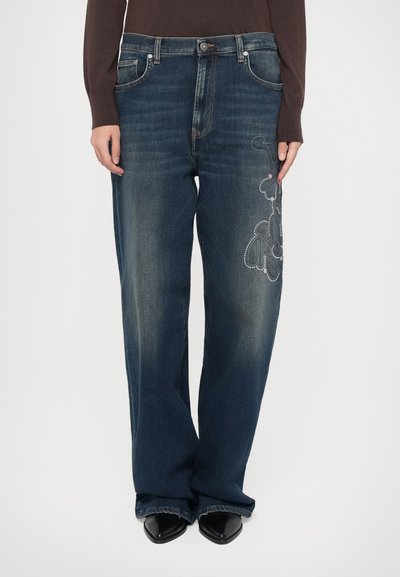 Dunkelblaue Jeans mit entspannter Passform, die dekorative Stickerei in einem wirbelnden Muster an der linken Oberschenkelseite und silberne Nietenakzente aufweisen.