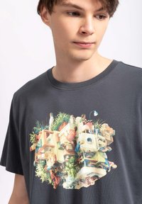 Grijs T-shirt met korte mouwen, voorzien van een kleurrijk bedrukt ontwerp van mensen en planten in een gestileerde, gestapelde opmaak. Gemaakt van katoen.