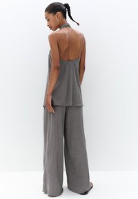 Gray, lightweight two-piece outfit featuring a halter neck top and wide-leg pants with a textured fabric and a flowing design.