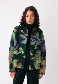 Kratka jakna s cvetličnim vzorcem v zeleni, vijolični in koralni barvi; narejena iz teksturirane tkanine z gumbi spredaj in visokim ovratnikom.