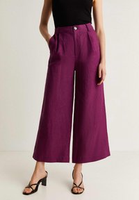 Zijde-brede broek in een levendige paarse tint, gemaakt van een gestructureerde stof. Voorzien van een knoopsluiting aan de voorkant en zijzakken.