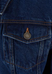 Poche de veste en jean bleu foncé avec couture orange et un bouton métal gravé avec "Urban Classics."