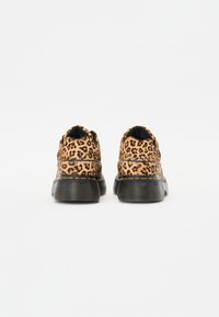 Zapatillas con estampado de leopardo y suela de goma negra, parte superior texturizada y detalle de costura amarilla a lo largo del borde de la suela.