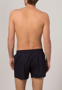 Marinblå badbyxor med elastiskt midjeband, tillverkade av lättviktsmaterial, med en enkel design och utan synliga mönster eller detaljer.