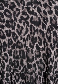 Gros plan sur un tissu à côtes avec un motif léopard noir et gris.
