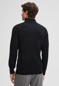 Maglione a collo alto nero a costine con maniche lunghe, caratterizzato da un design aderente e una texture sottile. Finitura liscia al collo e ai polsini.