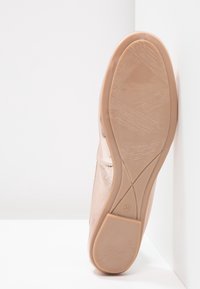 Zapato plano sintético rosa con parte superior texturizada y suela de goma, que presenta un acabado suave y un diseño minimalista. Talla 36 indicada en la suela.