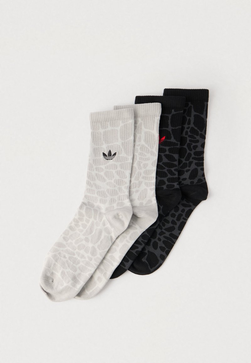 Három pár zokni: egy világosszürke, strukturált mintával és fekete logóval, valamint kettő fekete hasonló mintával, az egyik piros logóval.