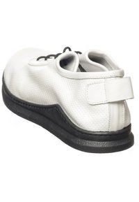 Zapato de piel perforada blanca con suela de goma negra, punta redondeada y diseño de cordones. Cuenta con una lengüeta trasera para ponerlo y quitarlo fácilmente.