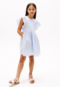 Svetlomodré šaty s volánovými rukávmi, priliehavým živôtikom a rozšírenou sukňou; majú bočné vrecká. Nosené s bielymi sandálmi.