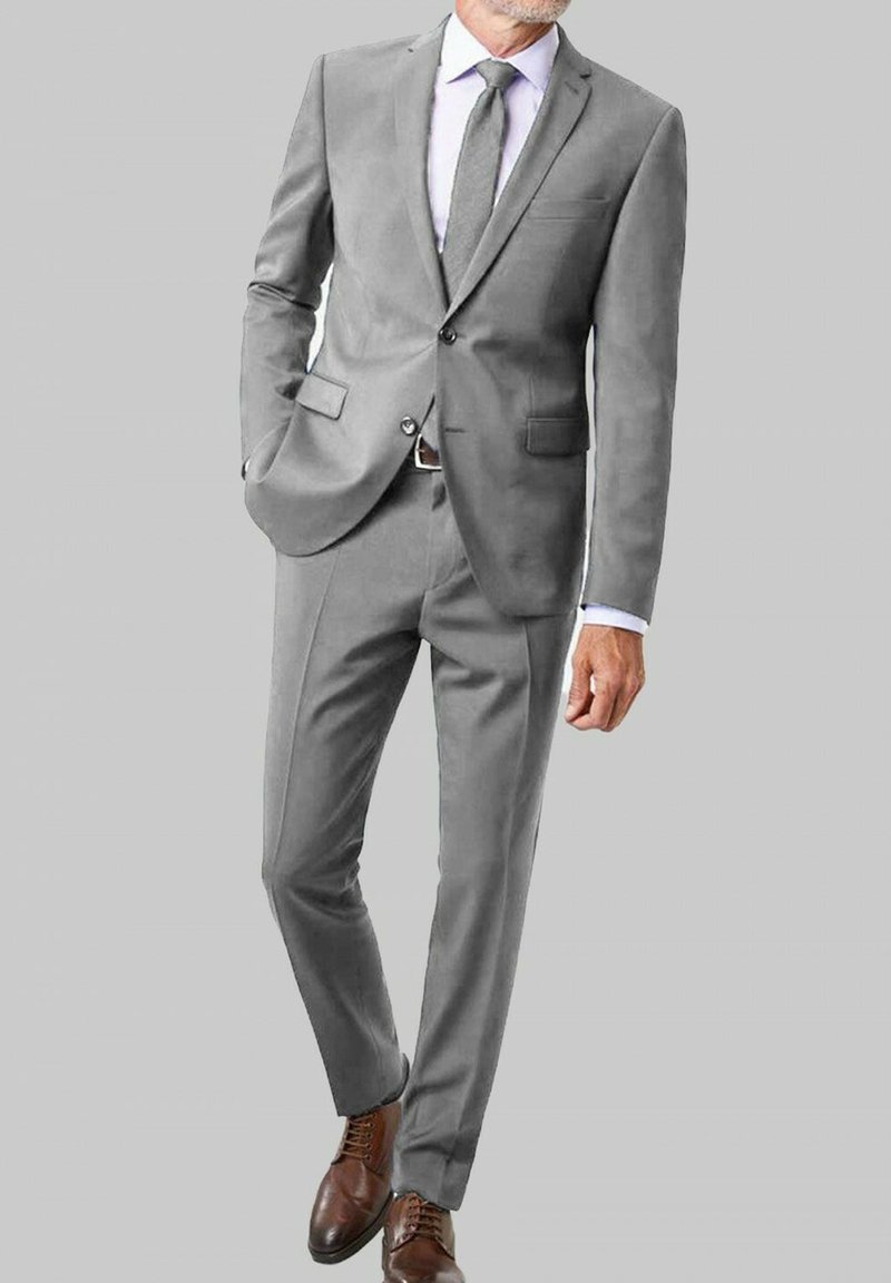 Costume gris clair au design ajusté, comportant deux poches avant, un blazer à un bouton, et un pantalon assorti. Chaussures en cuir marron.