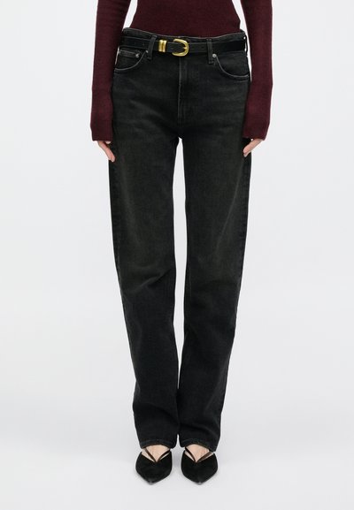 Čierne džínsy s rovnými nohavicami a klasickým päťvreckovým dizajnom, doplnené čiernym opaskom so zlatou prackou a textúrovaným vínovo červeným topom.