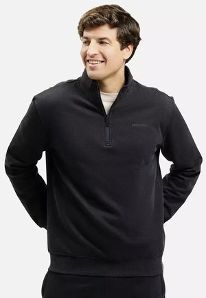 Czarny sweatshirt z pół zamkiem błyskawicznym, z długimi rękawami, z miękkiego materiału. Posiada ściągacze na mankietach i dolnym końcu oraz minimalistyczne logo na piersi.