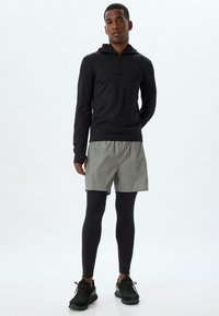 Svart långärmad zip-up hoodie, ljusgrå shorts, svarta leggings och svarta träningsskor. Slätt tyg, sportig design, mångsidigt lageralternativ.