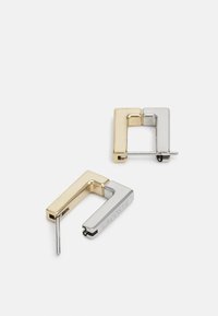Pendientes de aro geométricos en oro y plata que presentan una forma cuadrada, textura suave y un detalle del logo en la pieza de plata.