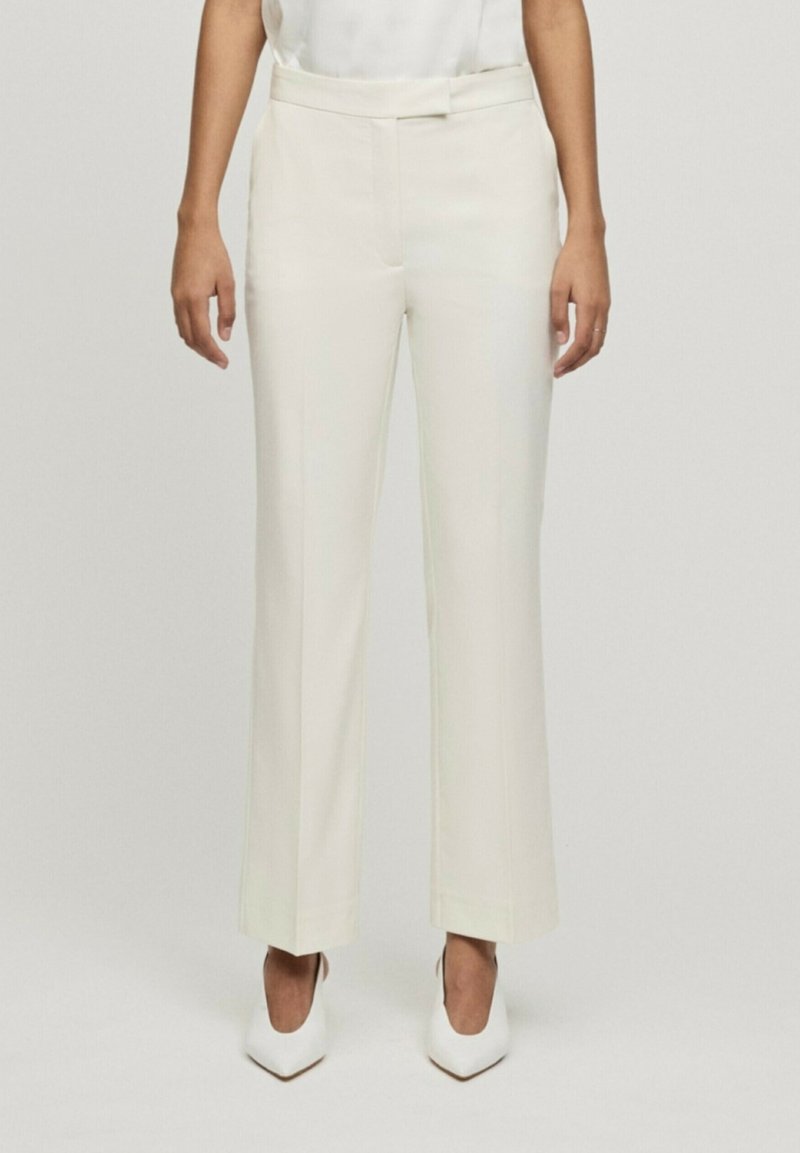 Pantaloni bianchi a gamba larga con una texture liscia, vita aderente e tasche laterali. Il tessuto ha una leggera lucentezza e un taglio sartoriale.