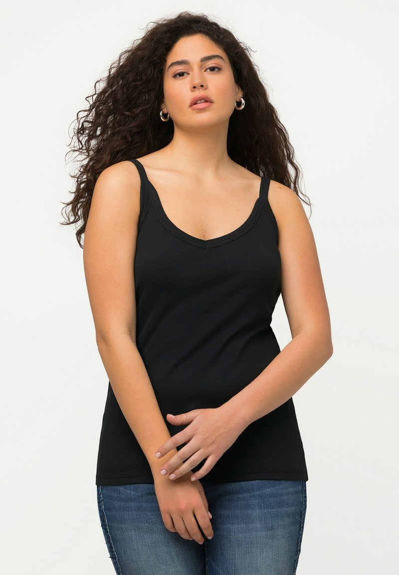 Top in cotone nero a coste con spalline larghe e scollatura a V, abbinato a jeans skinny blu. Tessuto leggero e design aderente.