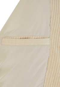 Béžová látka se svislou vroubkovanou texturou na jedné straně a hladkým povrchem na druhé. Obsahuje skrytá kapsa s nenápadným švem.